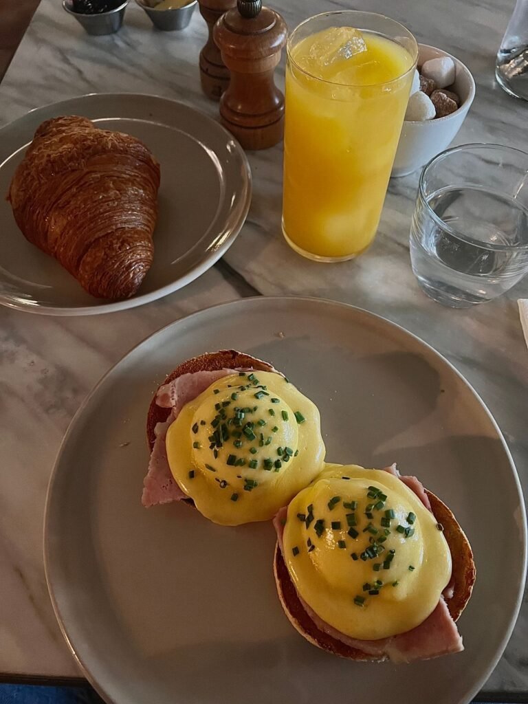 Eggs benedict with croissant and orange juice on a breakfast table