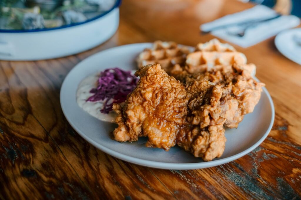 Fried chicken with waffles and fresh coleslaw on a rustic table