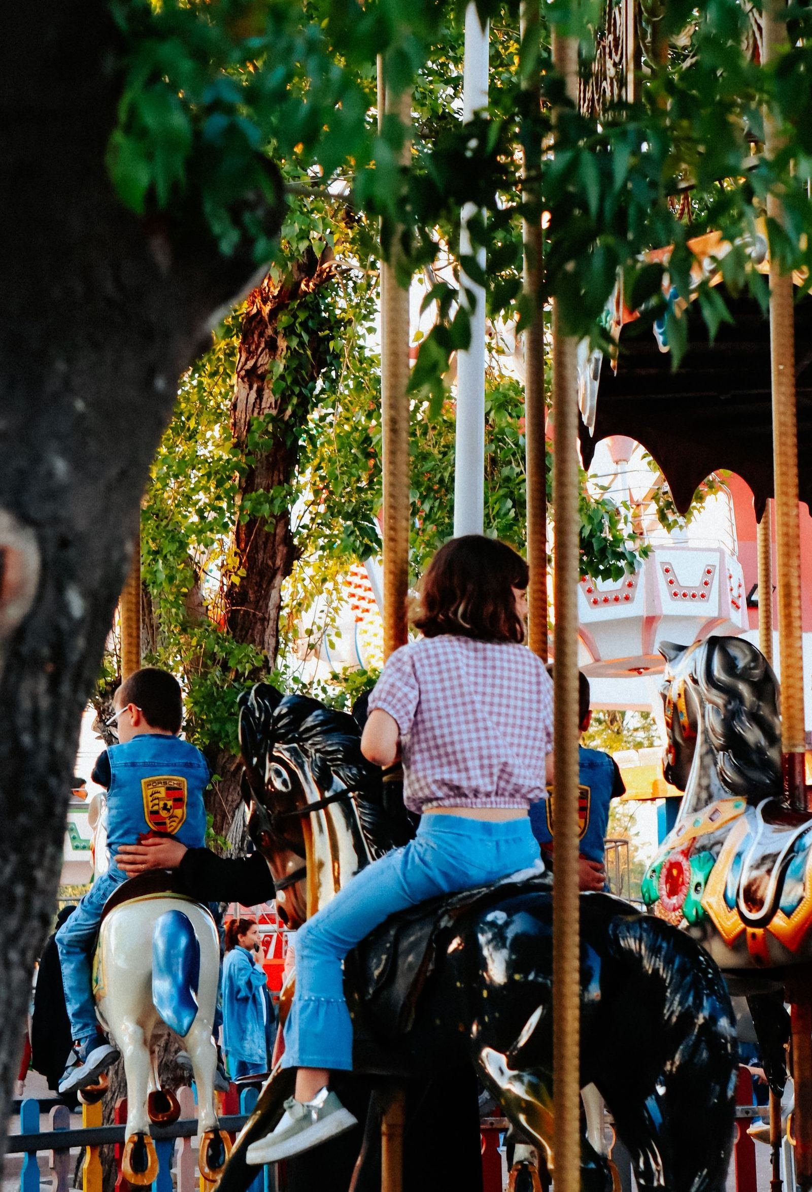 Children riding painted carousel horses on a classic outdoor carousel