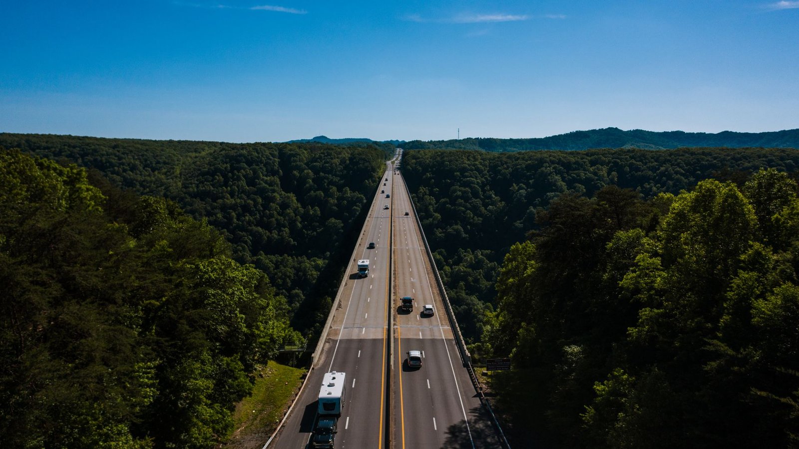 Aerial view of vehicles on a highway through green Appalachian forest