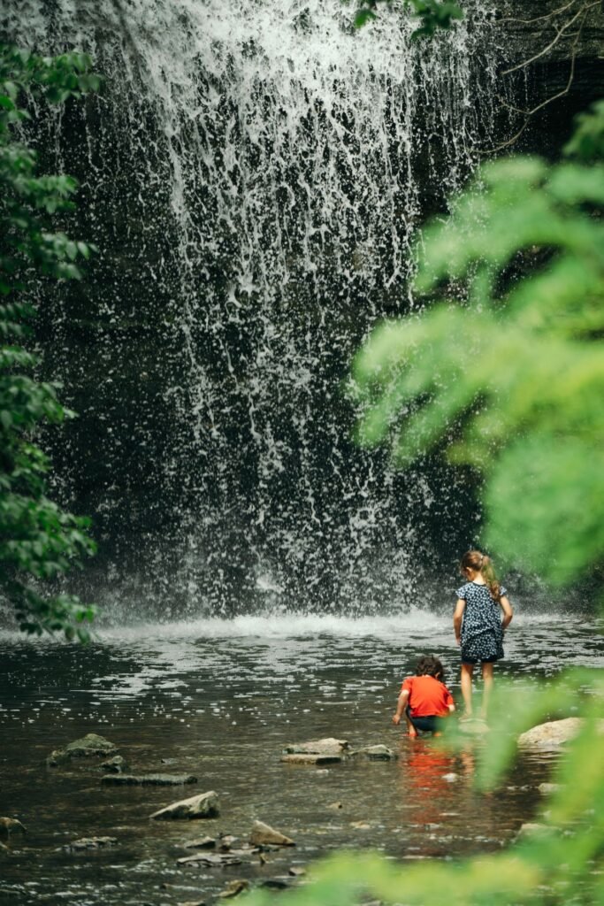 Kids playing at the base of a small waterfall in a North Carolina forest
